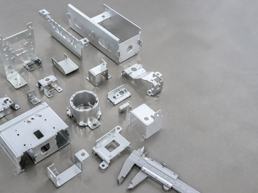 Assorted aluminum stamped parts with calipers on an inspection surface