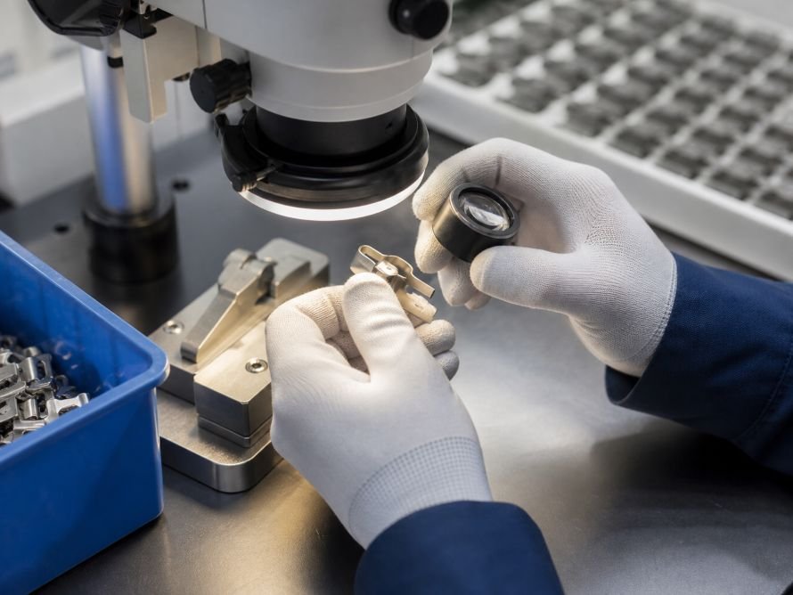 What Causes Burrs in Metal Stamping Parts? 3 Technician inspecting the edge of a stamped metal part for burrs